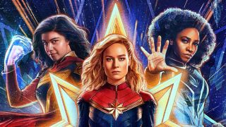 The Marvels all standing together. From left to right: Ms. Marvel (teen, long dark hair, glowing fist raised in attack position), Captain Marvel (long blonde hair, looking directly ahead with a steely gaze) and Monica Rambeau (Dark tightly curled hair, hand held up palm forwards with fingers outstretched).