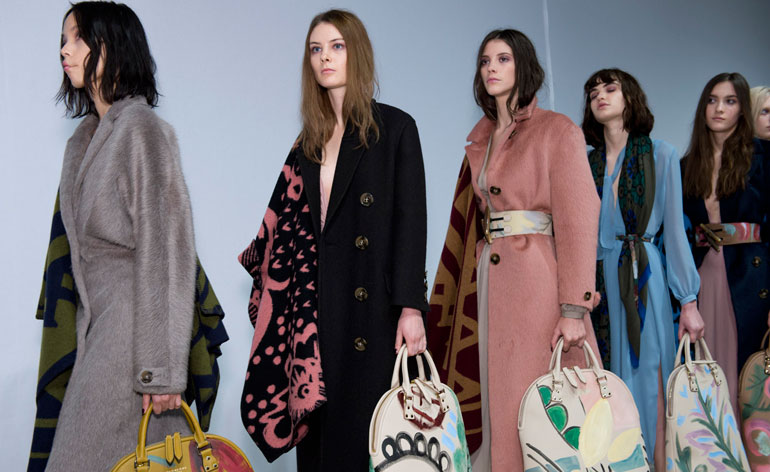 Women waiting in a line wearing patterned outfits and bags
