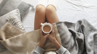 woman drinking tea in a cozy bed