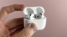 AirPods 4 with the case open, held in a man's hand