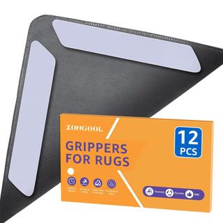 The underside of a rug corner with gripper tape next to an orange package