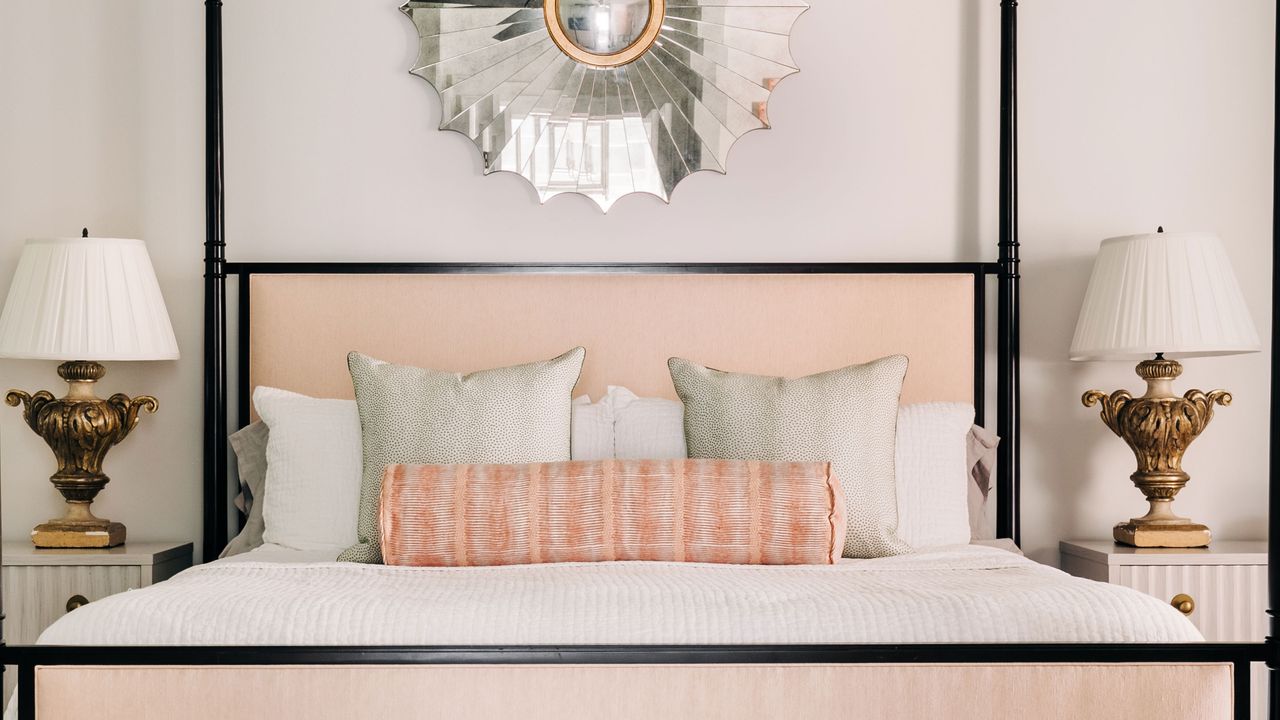 modern style double four-poster with black posts and coral cushions with brass based bedside lamps