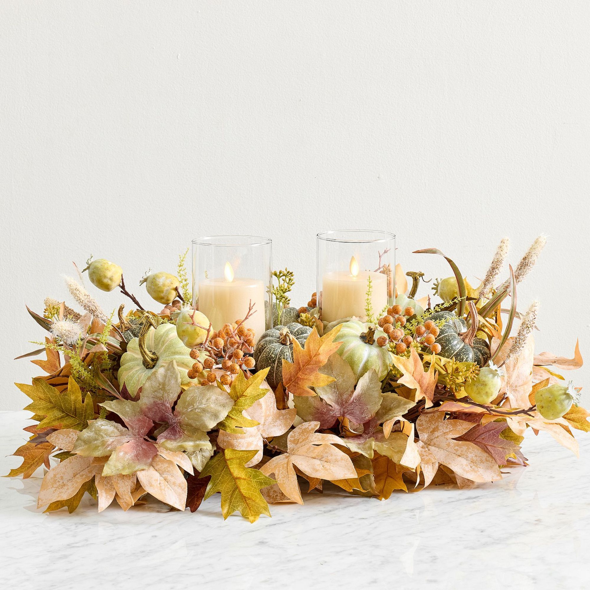 Faux floral fall centerpiece with leaves, flowers and pillar candles