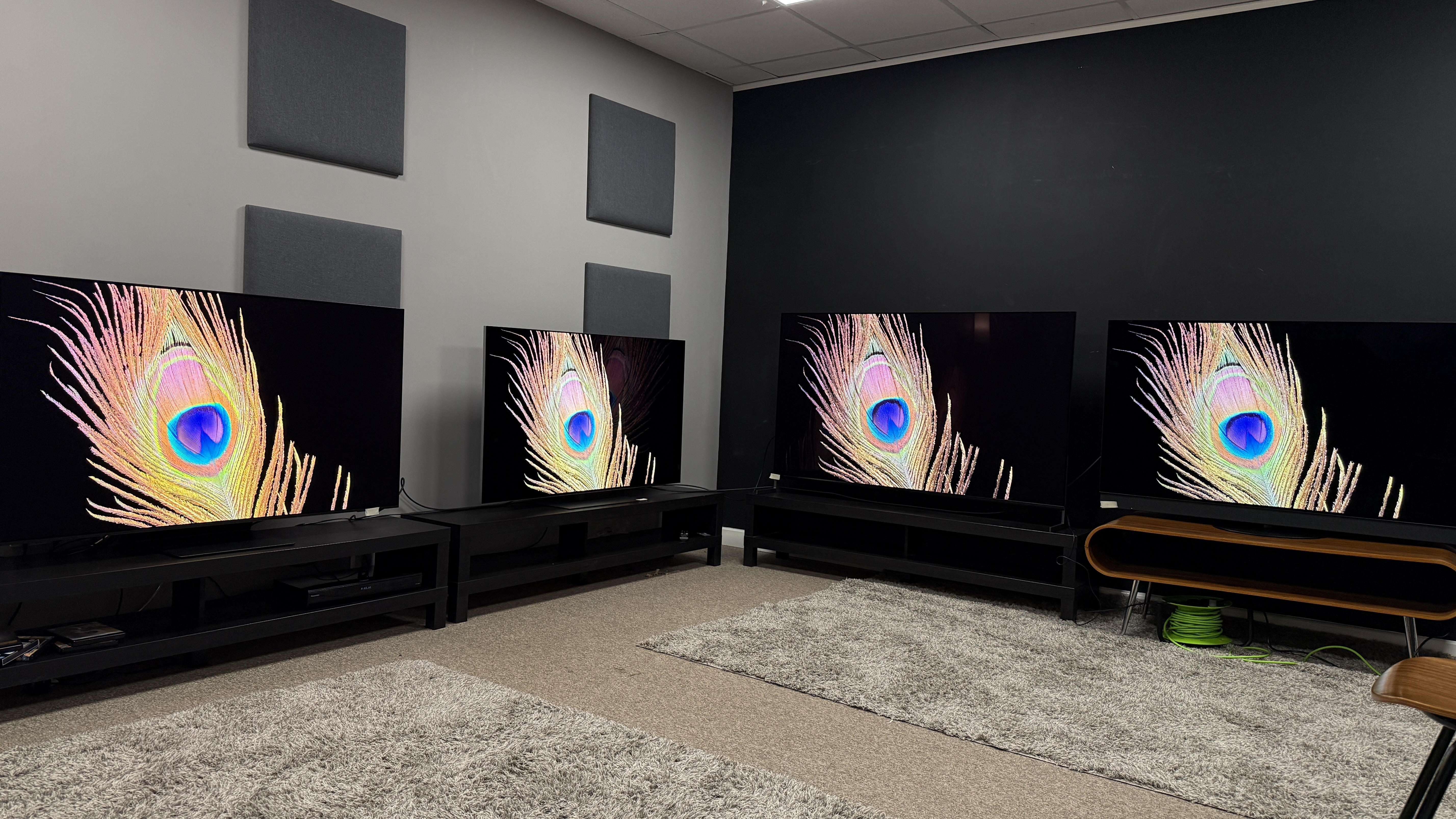 Samsung S95F (far left), LG G5 (middle left), Sony Bravia 8 II (middle right), Panasonic Z95B (far right) OLED TVs all displaying a peacock feather against a black background on screen