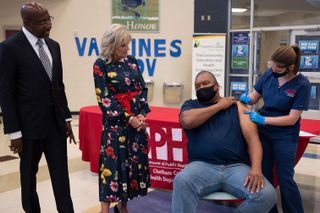 US First Lady Jill Biden looks on with US Senator Raphael Warnock (L), D-GA, as Alfred Lee Smith (C) is vaccinated with the Johnson & Johnson COVID-19 vaccination at a vaccination facility at Alfred E. Beach High School in Savannah, Georgia, on July 8, 2021.