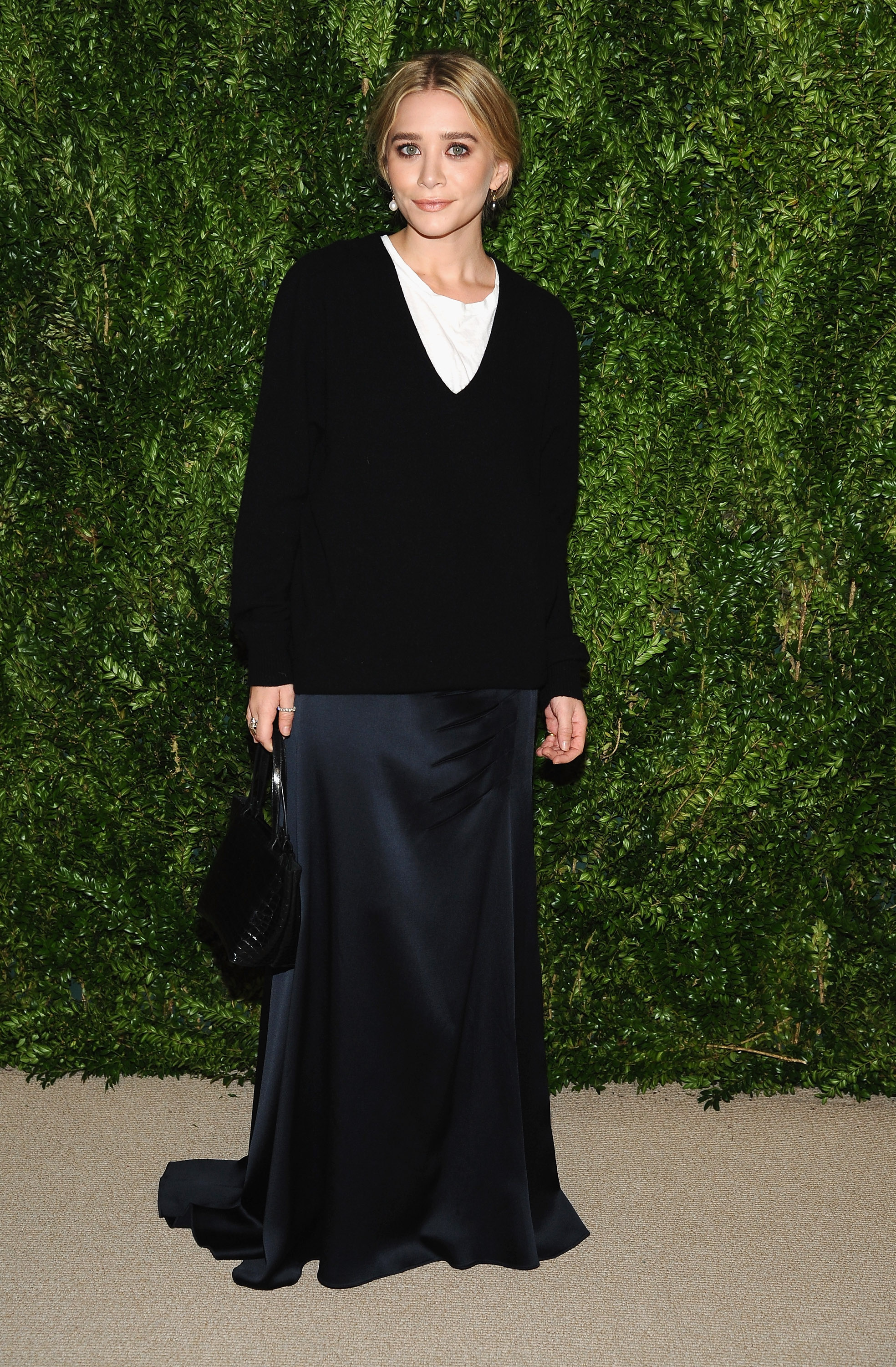 Ashley Olsen wearing a black v-neck sweater over a white T-shirt and black silk skirt to a Vogue x CFDA event in 2013