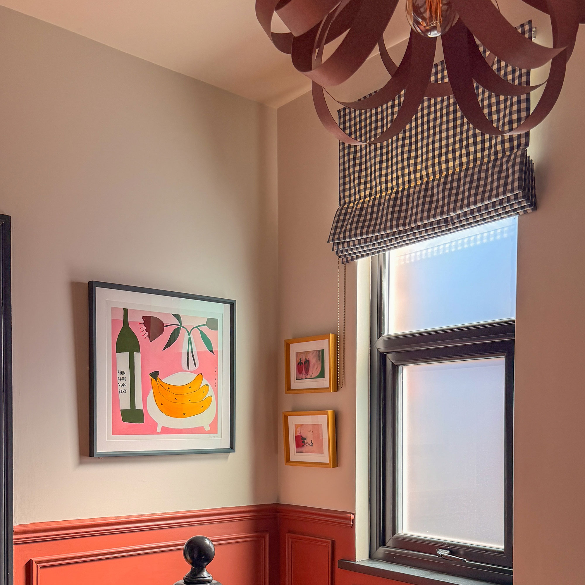 Neutral hallway with terracotta lower panelling, framed art on walls and gingham blind over window