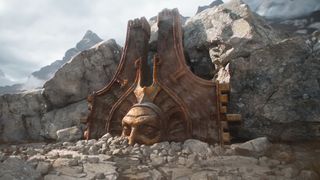 A screencap of the Path of Exile 2: Return of the Ancients teaser trailer. The head of a bronze statue is half-buried in rubble with sunlight shining down upon it.