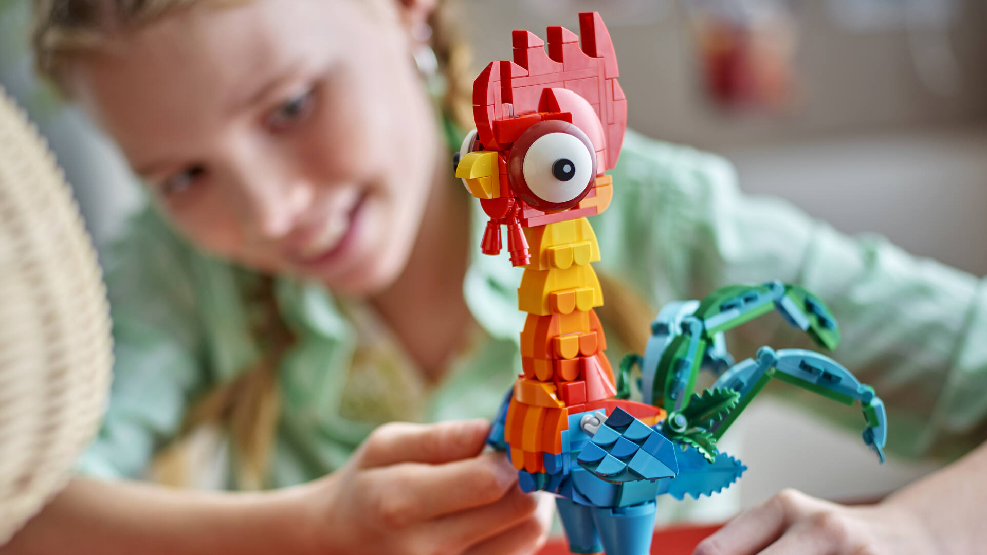A girl smiles while placing a piece on Lego Heihei