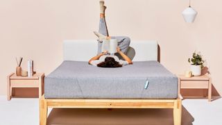 Best mattress in a box: image shows a woman with dark hair lying on the Siena Memory Foam Mattress in a box while reading a book
