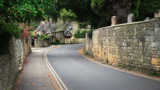 Picturesque road leading up to stone church in the Cotswolds, England
