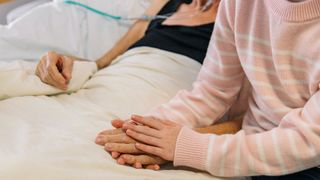 woman holding the hand of a relative or close friend in hospital