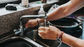 woman getting a glass of water from the tap