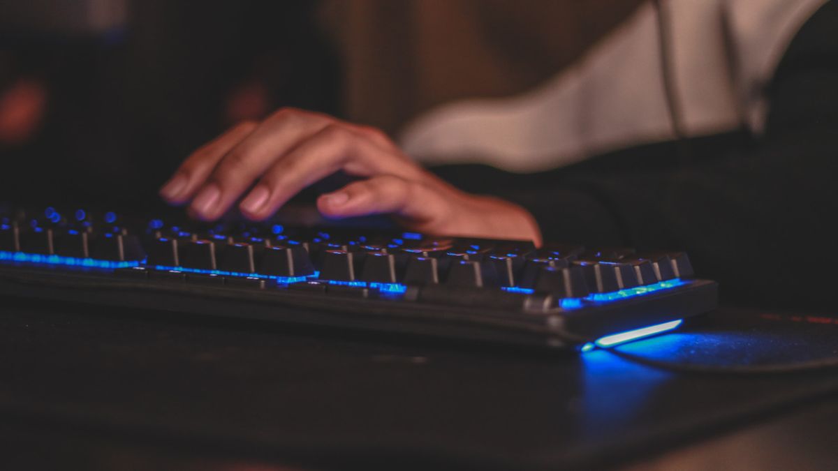 Hand on gaming keyboard with blue backlight