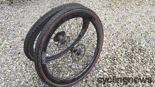 A pair of black Zipp wheels with tanwall tyres on some gravel