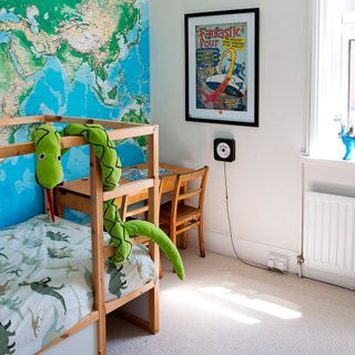 children bedroom with world map designed wall wooden bed wooden desk with chair and frame on wall