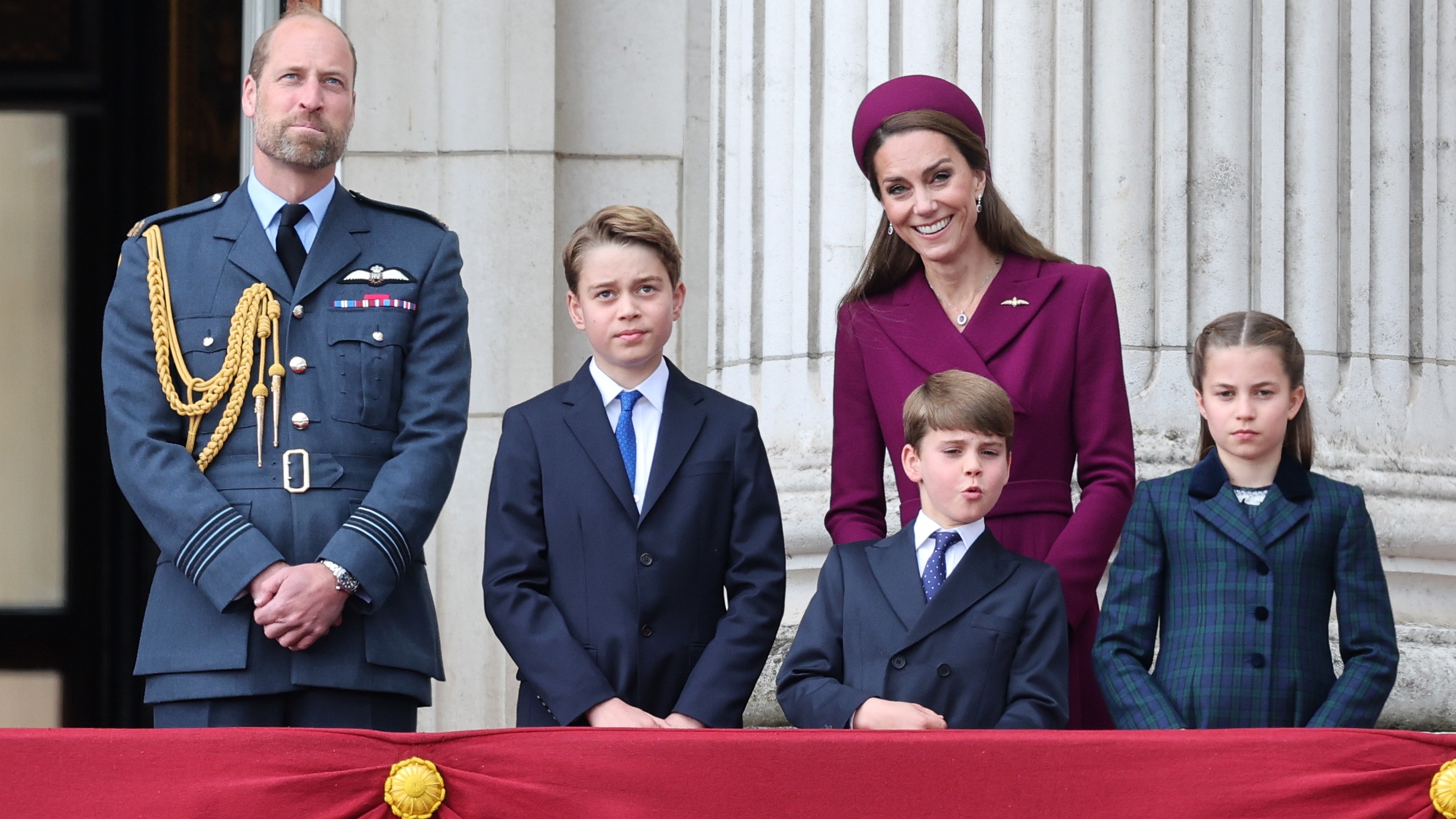 Prince William, Prince of Wales, Prince George of Wales, Prince Louis of Wales, Catherine, Princess of Wales and Princess Charlotte of Wales stand on the balcony of Buckingham Palace during the military procession to mark the 80th anniversary of VE Day