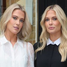 Amelia and twin sister Eliza Spencer wearing black and white tops and smiling at the camera in front of a shop window