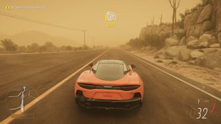 A screenshot from Forza Horizon 5 showing a McLaren supercar in a sandstorm