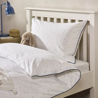 A white duvet set with small black stars in a kids bedroom