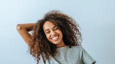 Portrait of woman with afro hair smiling with white wall background - stock photo