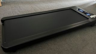 The JTX Movelight under-desk treadmill pictured on grey carpet