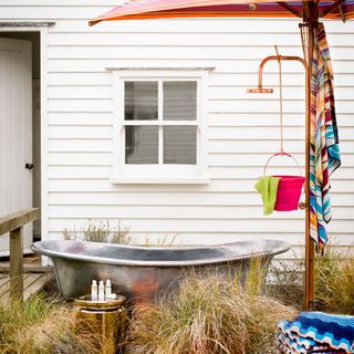 outdoor bathroom with silver bathtub and geometric towels