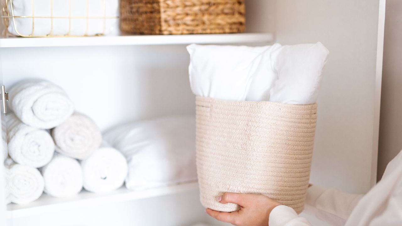 Woman putting basket into linen closet