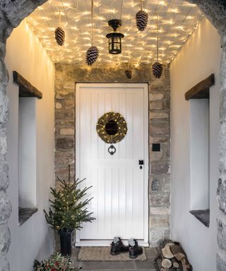A white front door with string lighting attached to the ceiling and a pendant light