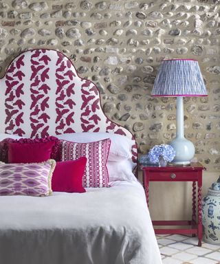 Patterned upholstered headboard with scatter cushions in a mix of printed and plain fabrics