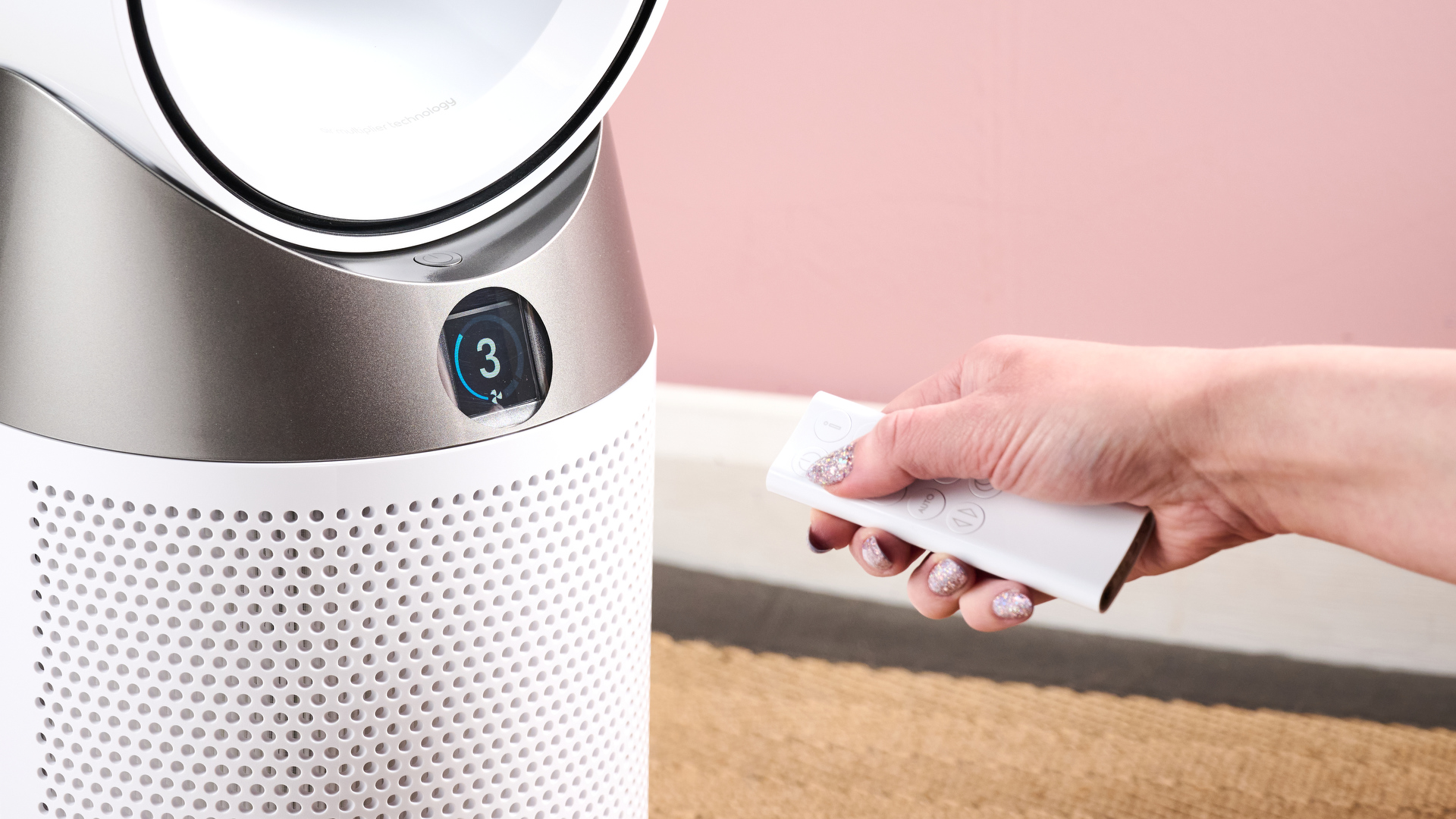 A woman is pointing the remote at the Dyson HP10.