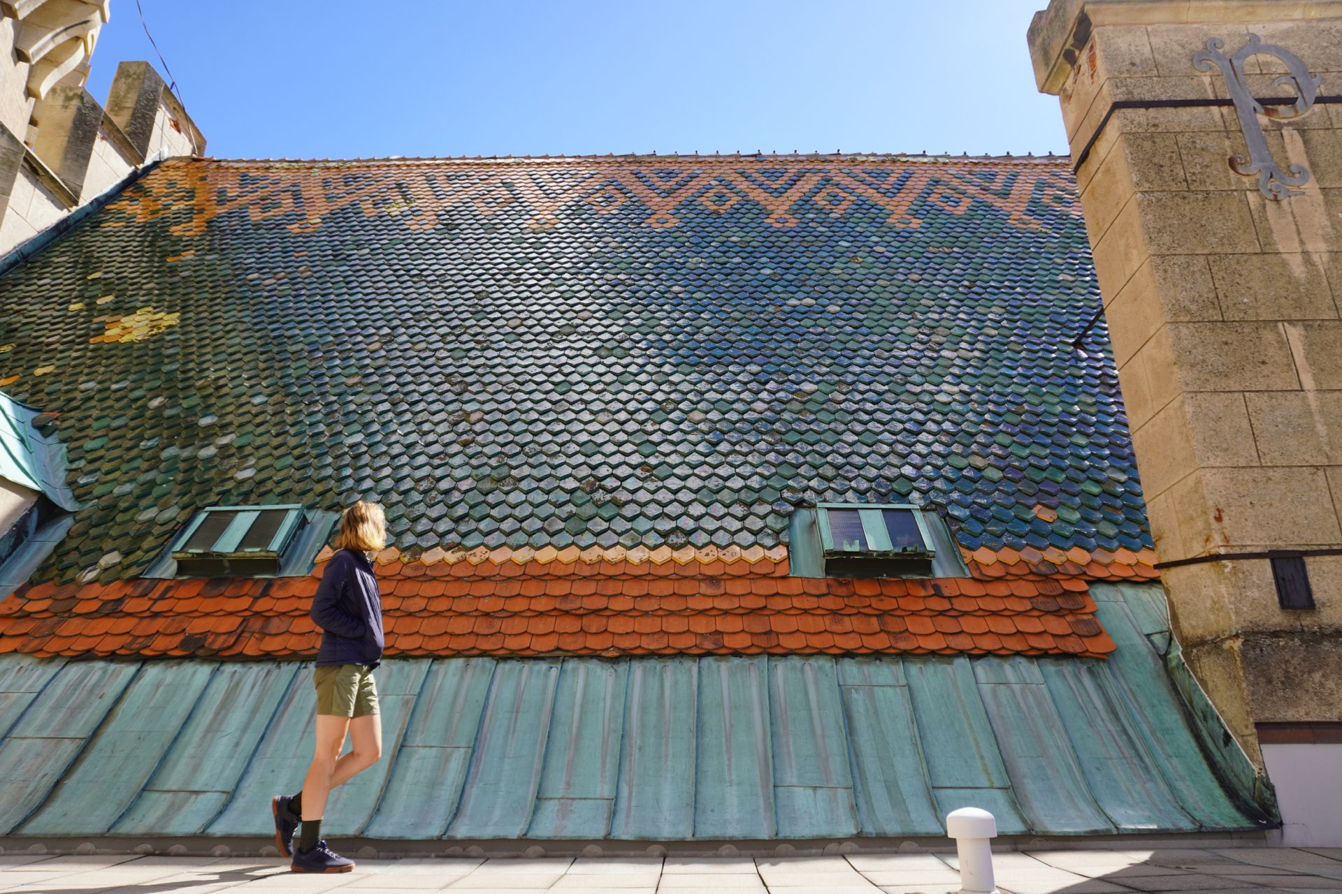 Image shows Anna walking by the tiled roof of the Castle of Spirits (Bojnice Castle) in Slovakia
