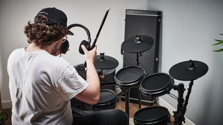 Man puts on headphones before playing his electronic drum set