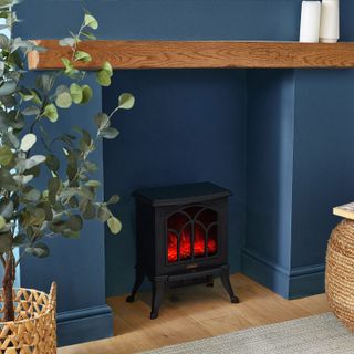 small electric stove in open fireplace with oak mantle