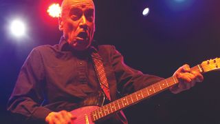 Wilko Johnson playing an electric guitar onstage.
