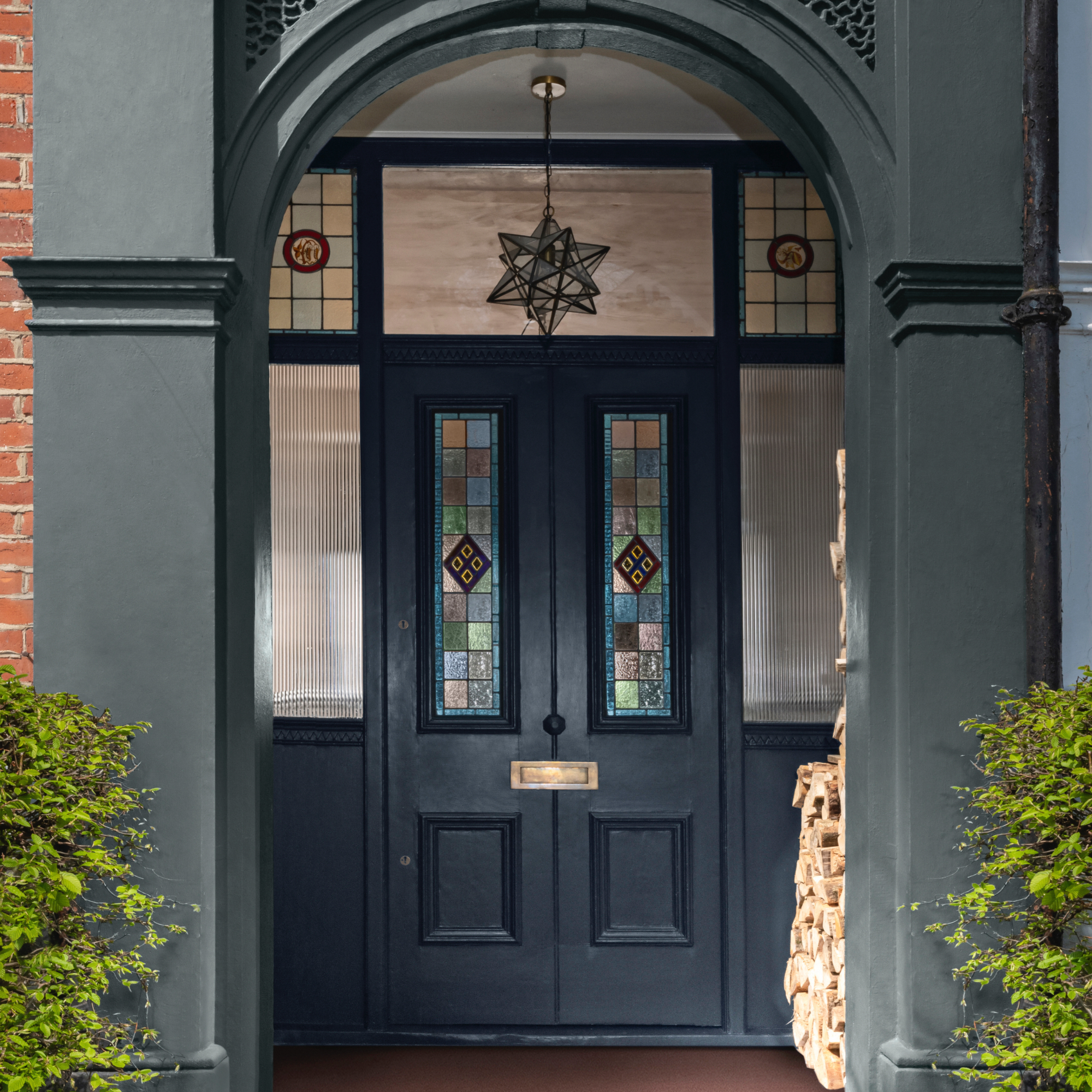 Dark blue front door with stained glass, pendant star light, dark grey painted masonry