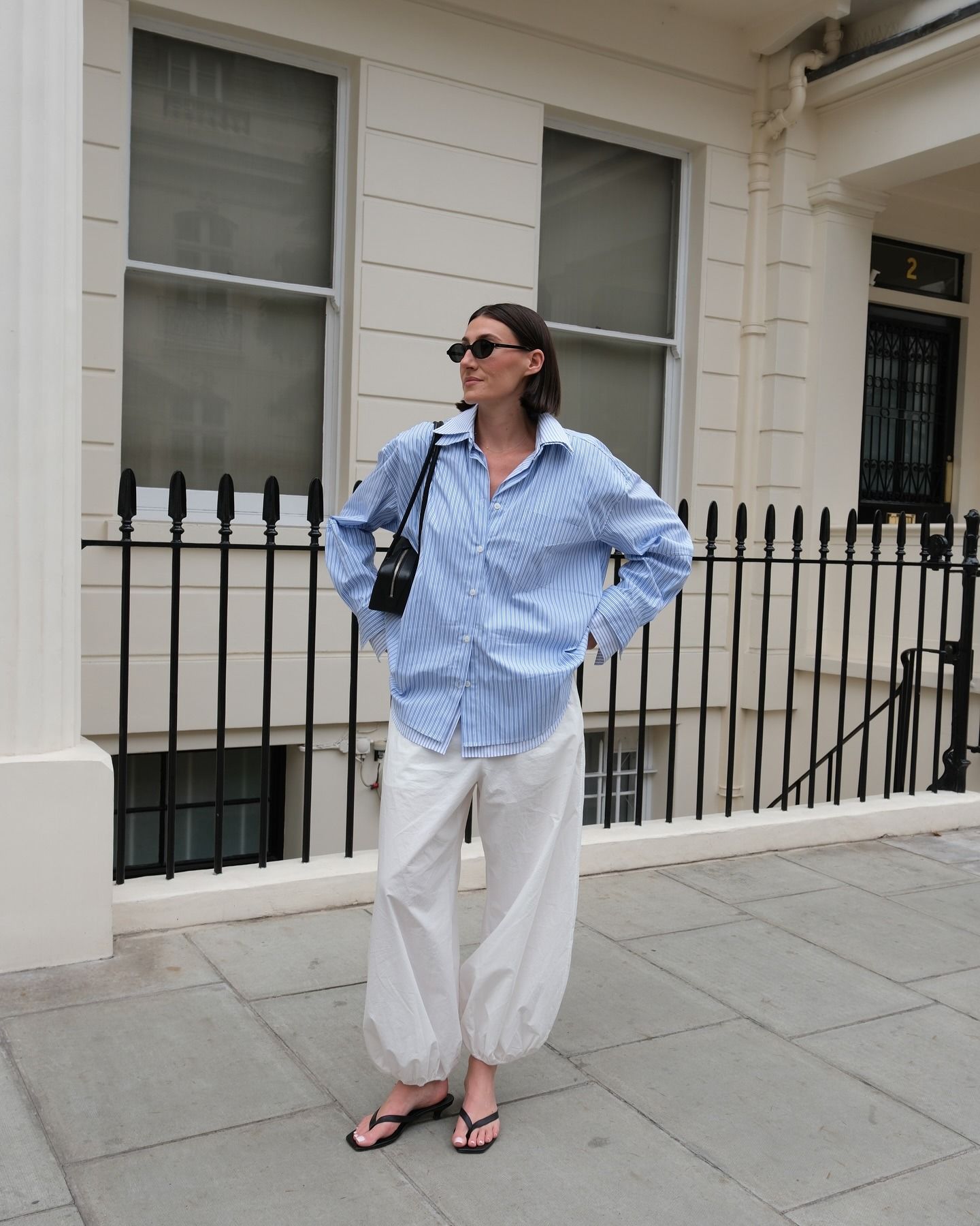 Influencer @sarahlouiseblythe wears balloon trousers with a blue shirt and black flip-flop heels.