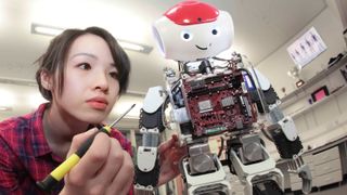 A woman building a small humanoid robot