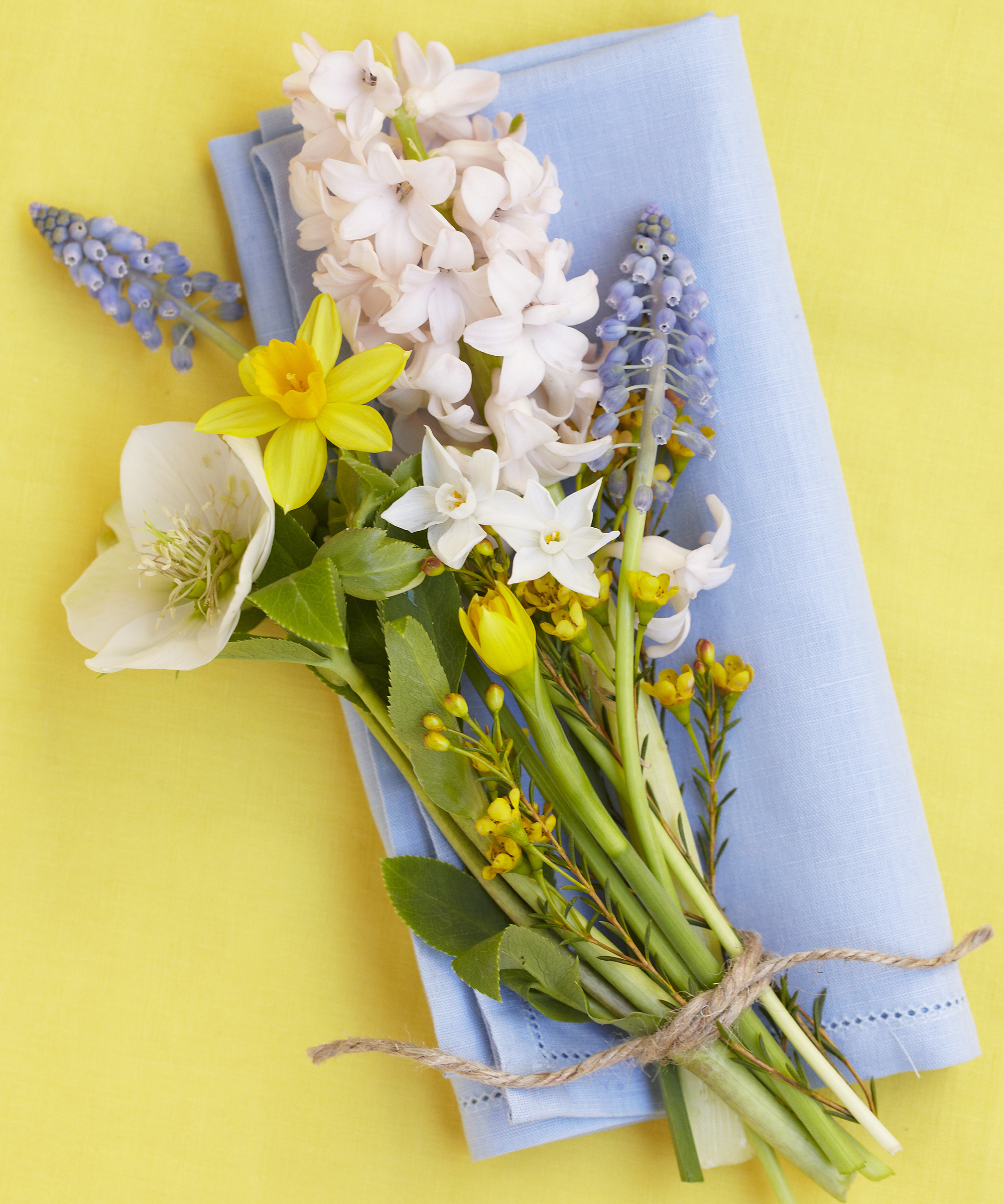 Mini bouquet of spring flowers with a blue napkin on a yellow background