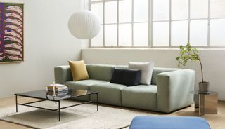 Pale green sofa with colourful cushions and paper pendant