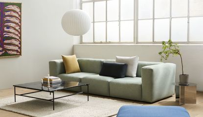 Pale green sofa with colourful cushions and paper pendant
