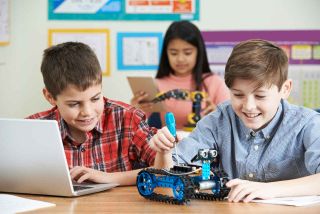 Two boys and a girl working with robots in the classroom