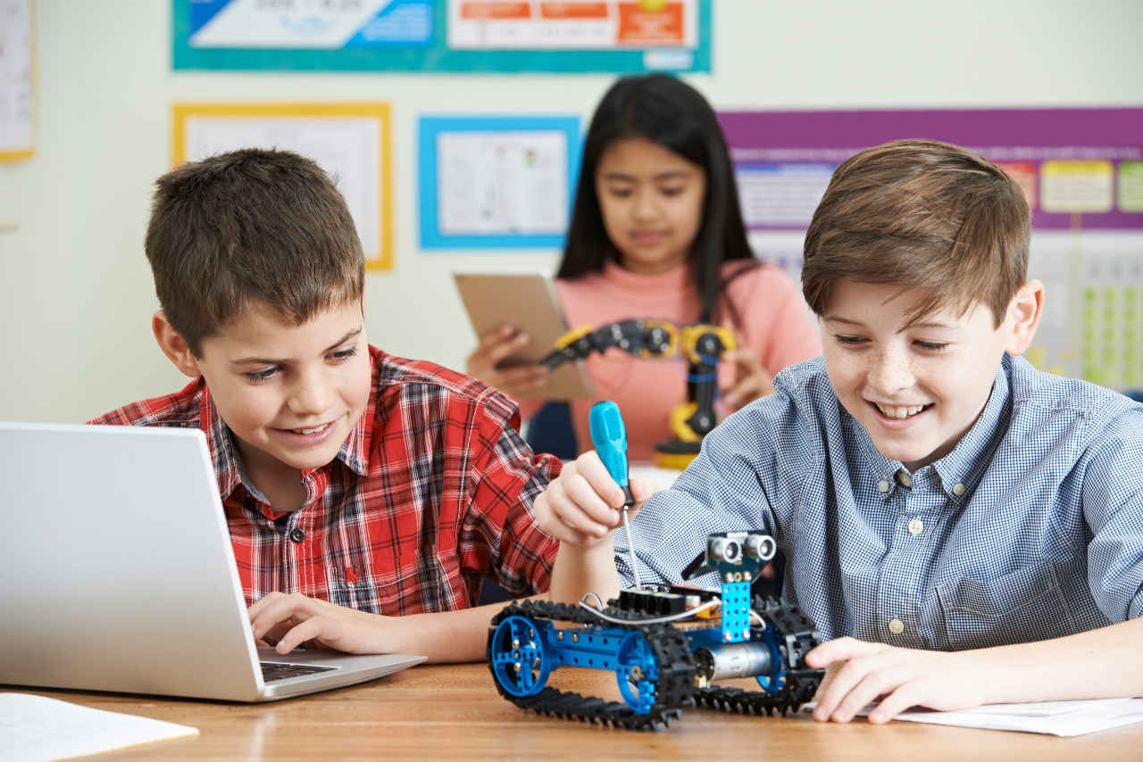 Two boys and a girl working with robots in the classroom