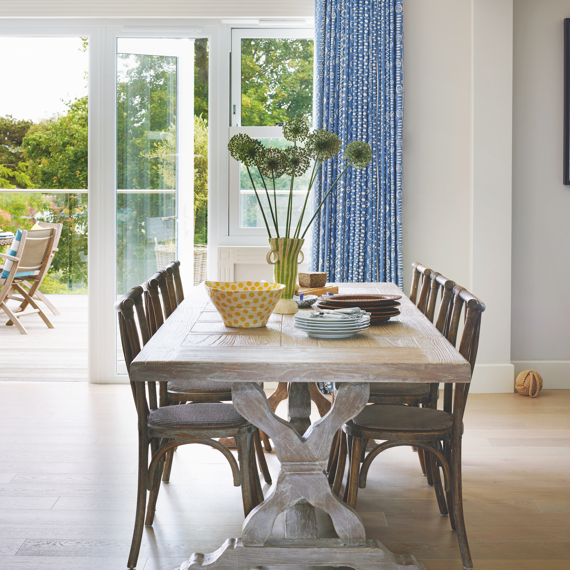 dining area with wooden dining table and wooden chairs with blue curtains and wooden floor