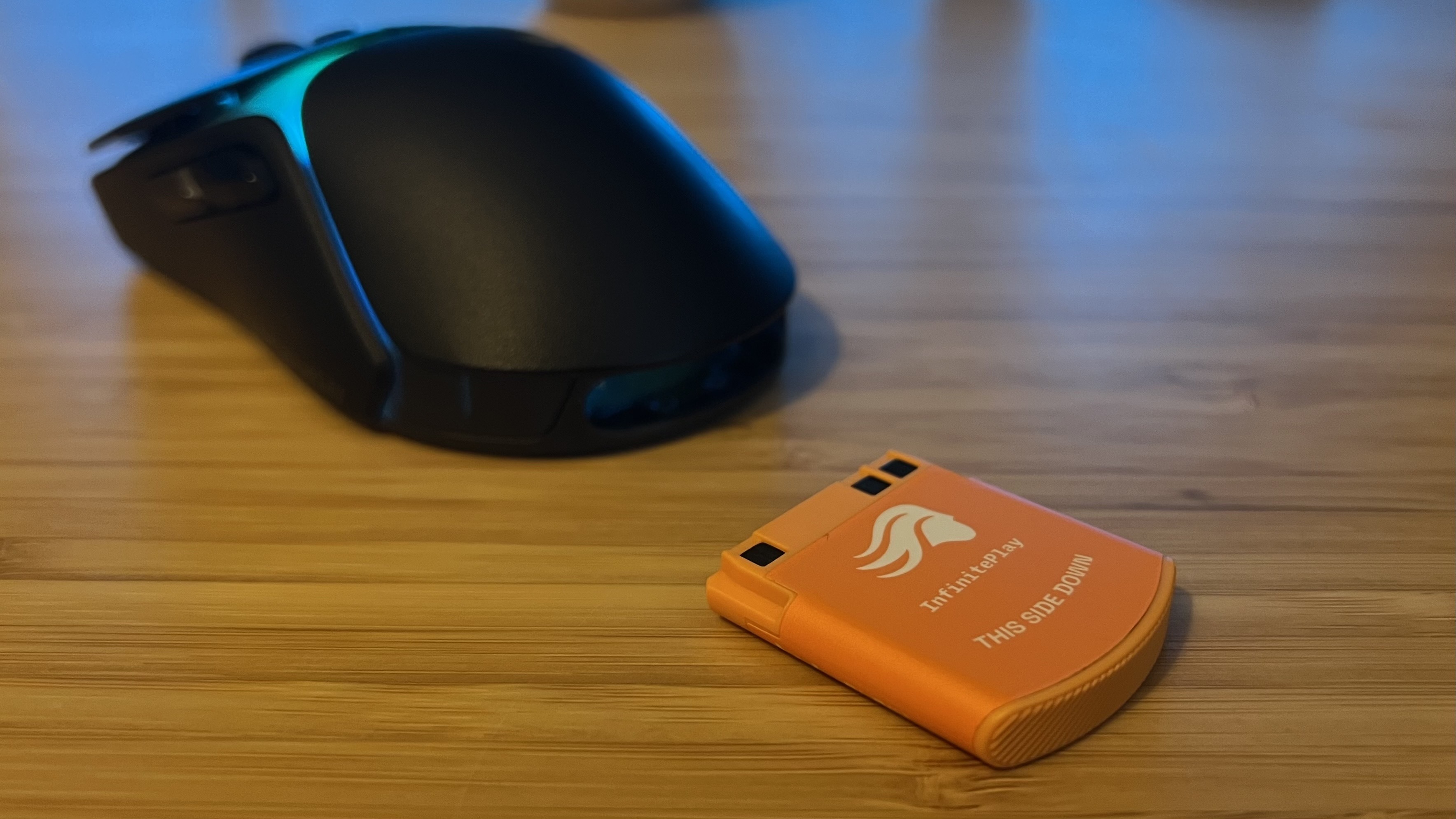 Glorious Model O 3 Wireless with battery removed and placed in front of it on a wooden desk