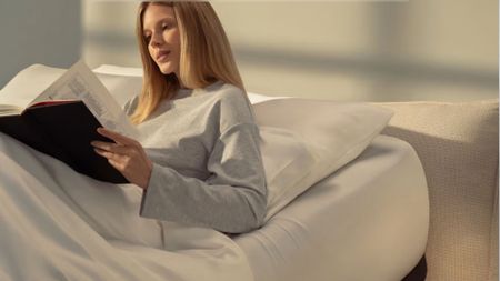 A blonde lady in bed with Eight Sleep Pod 5 Ultra+ in elevated head position reading 
