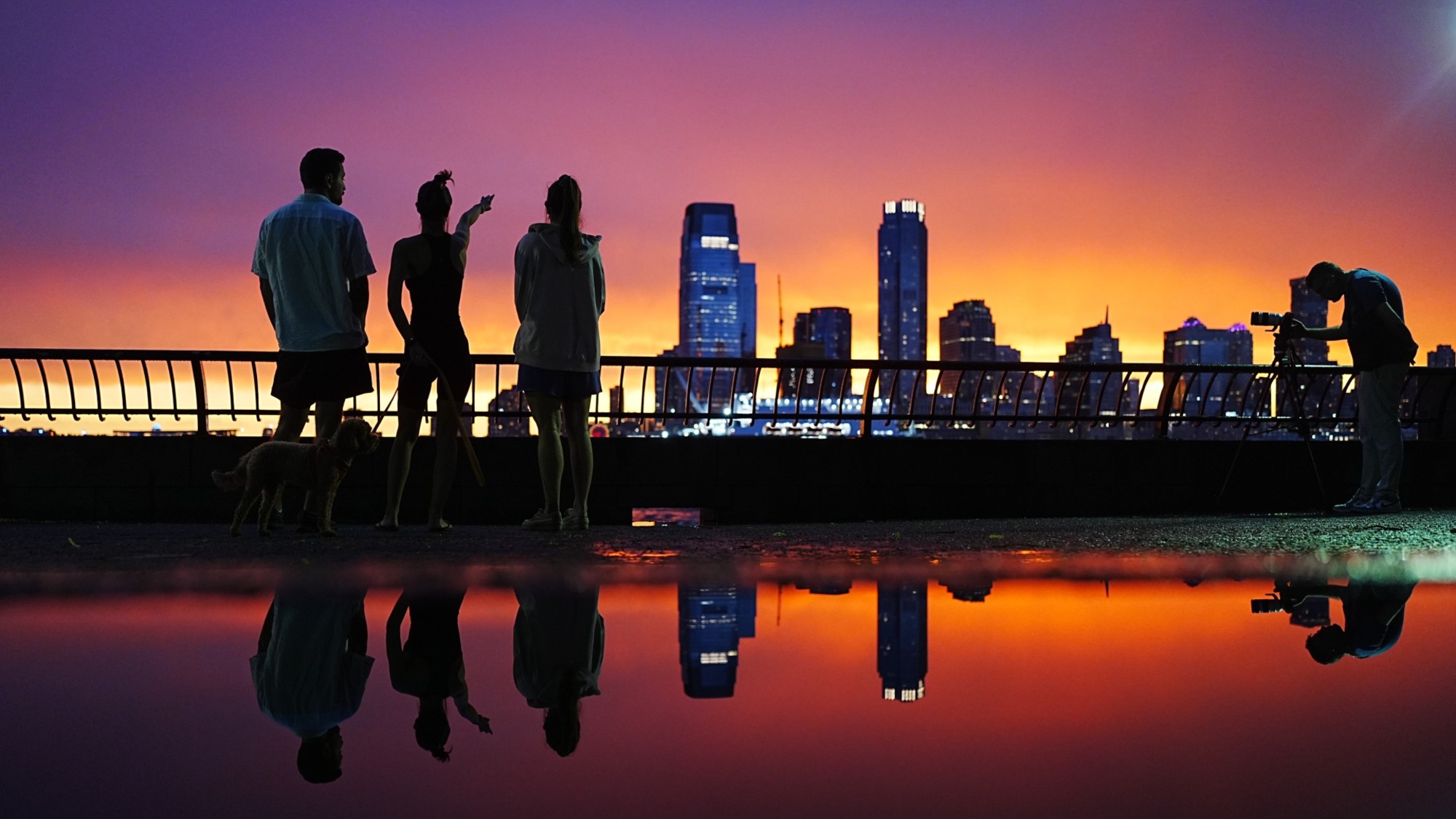 People watch a summer sunset across the harbor in New York City. 