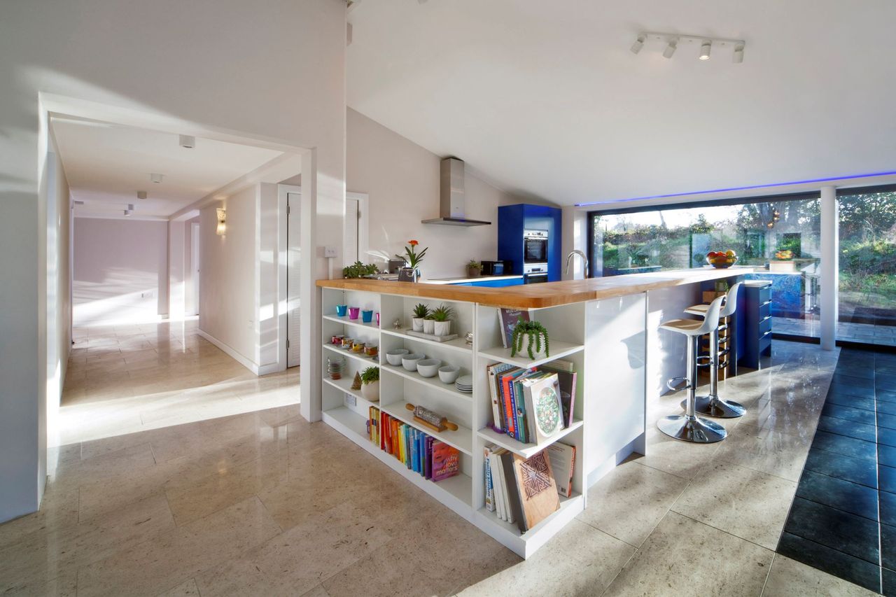 The kitchen island is linked to a bookshelf and is a mix between a kitchen and a diner with state of the art designs