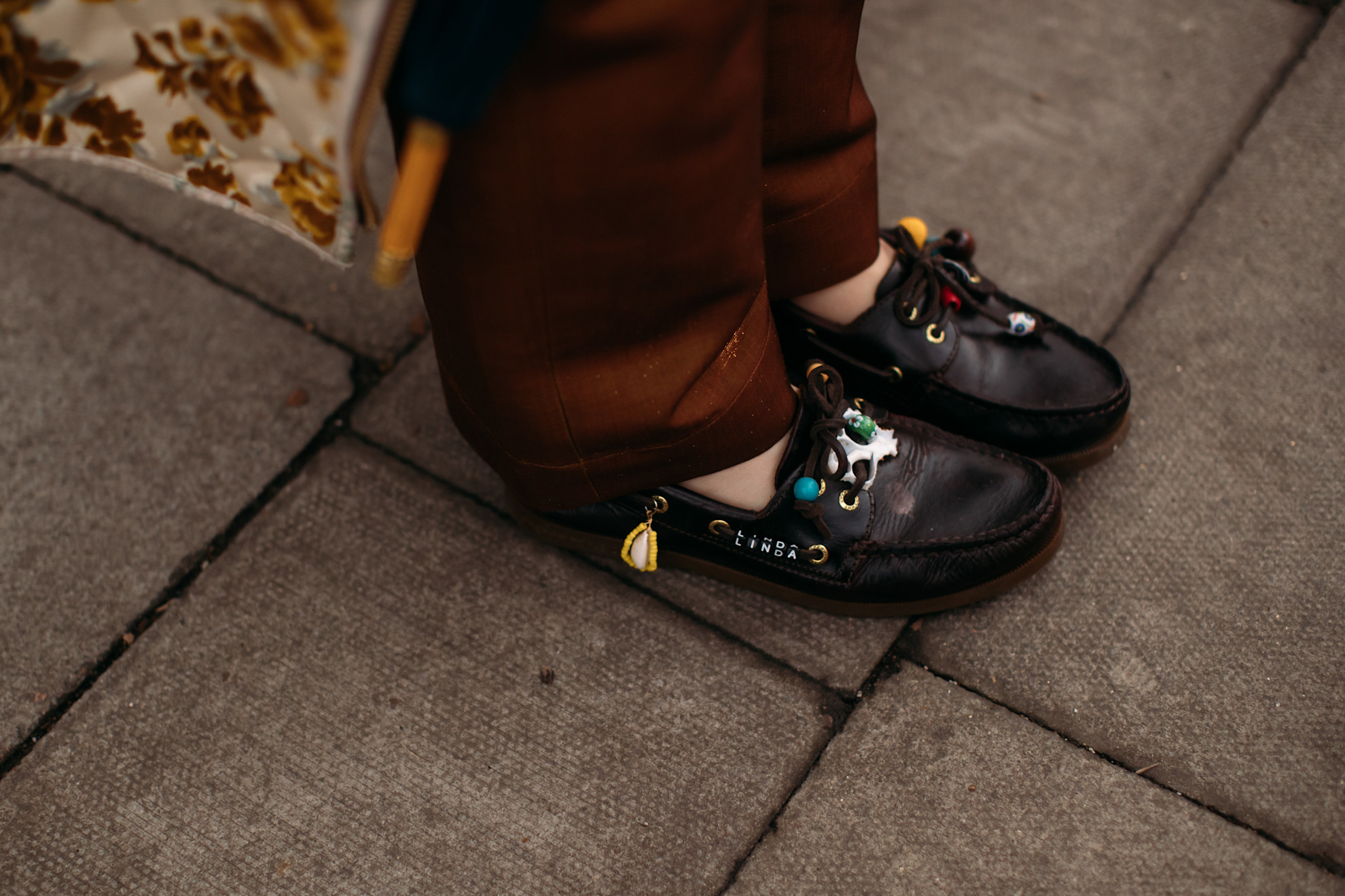 a close-up photo of brown boat shoe loafers with charms and beads attached