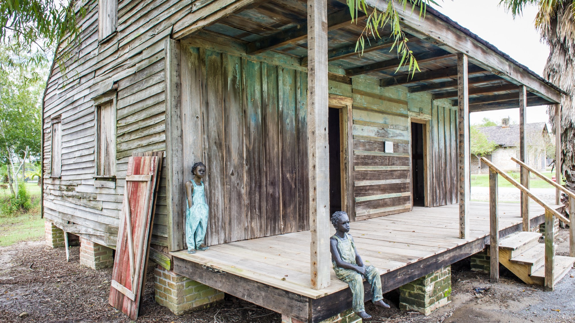 Sculptures of enslaved children outside of a slave cabin at Whitney Plantation